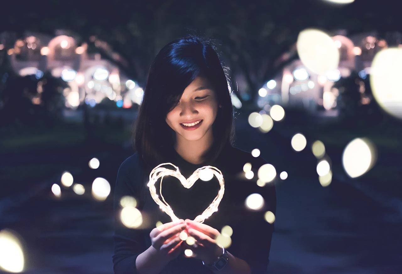 Woman holding a heart of lights in her hands