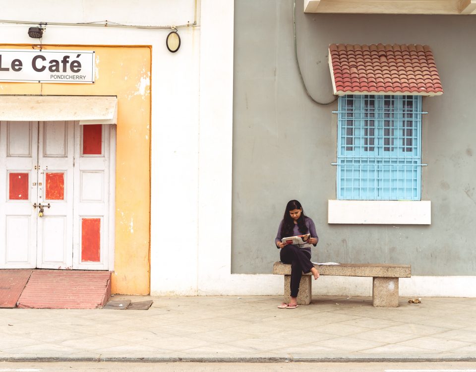 Frau sitzt auf einer Bank vor einem Gebäude vertieft in eine Arbeit