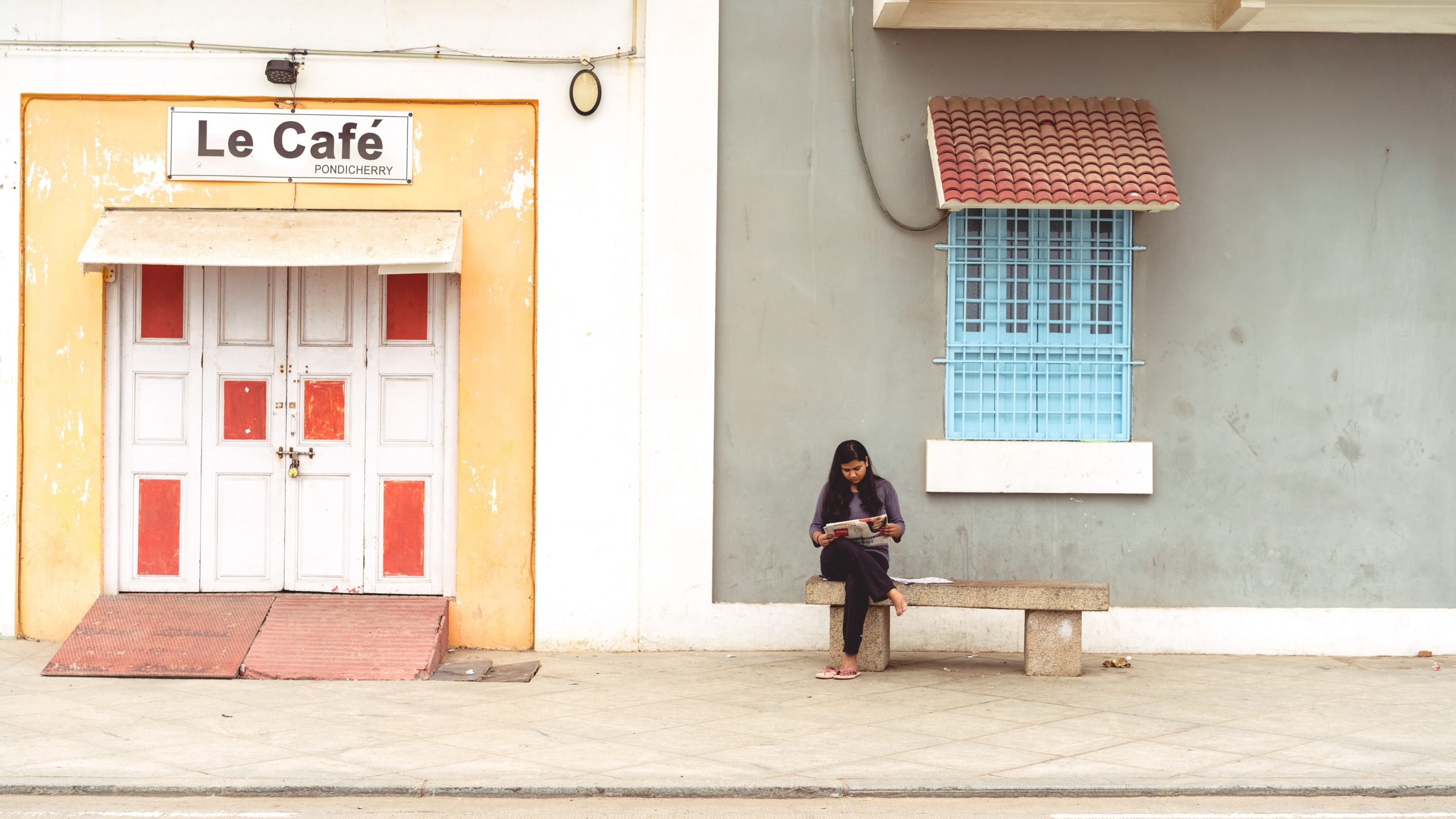 Frau sitzt auf einer Bank vor einem Gebäude vertieft in eine Arbeit
