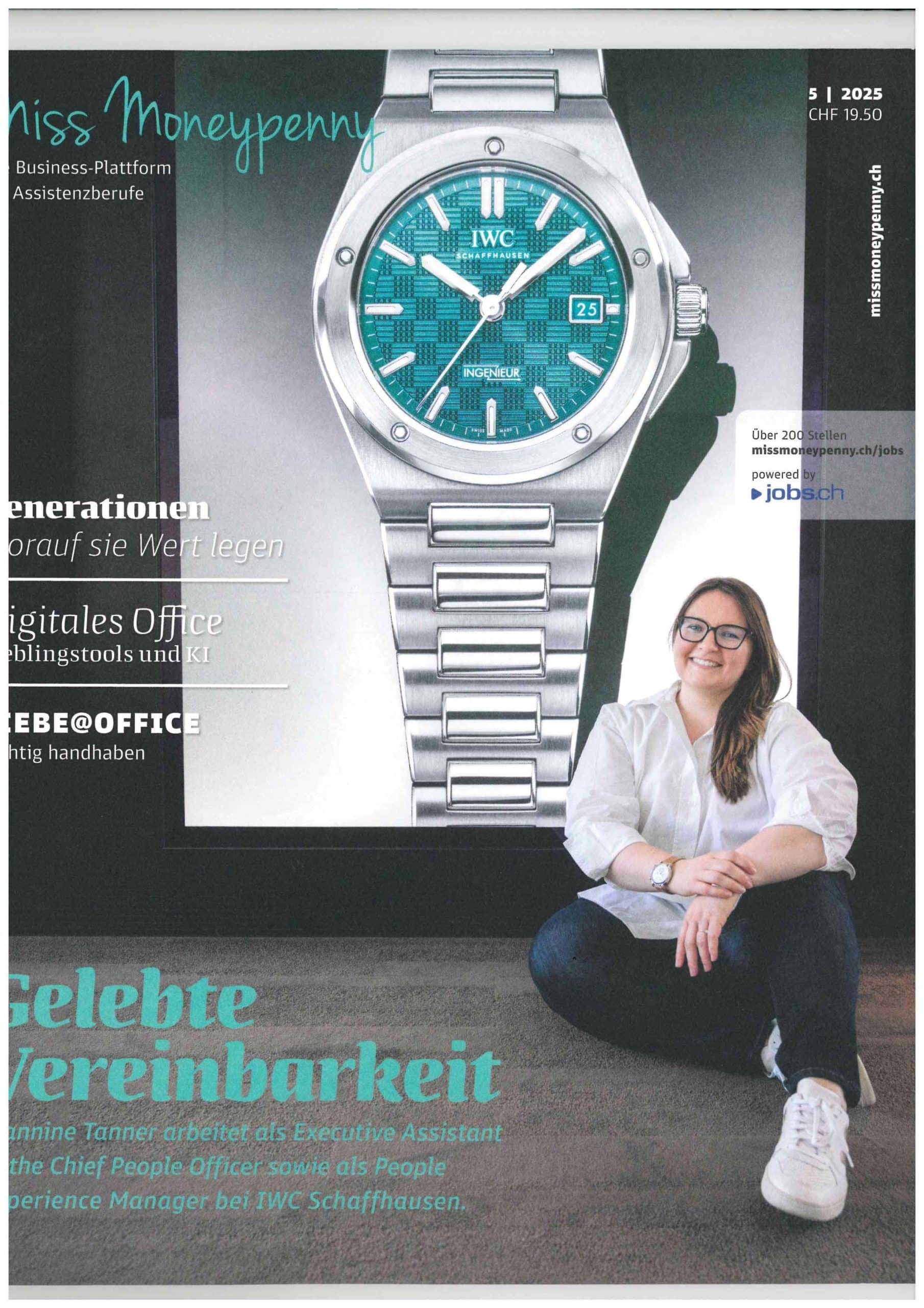 Friendly person with glasses sitting on the floor, smiling, in front of a large advertisement for a women's watch.